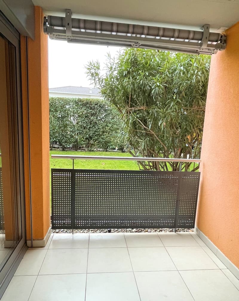Terrace, black railing, white tile floor, glass doors, outdoor vegetation