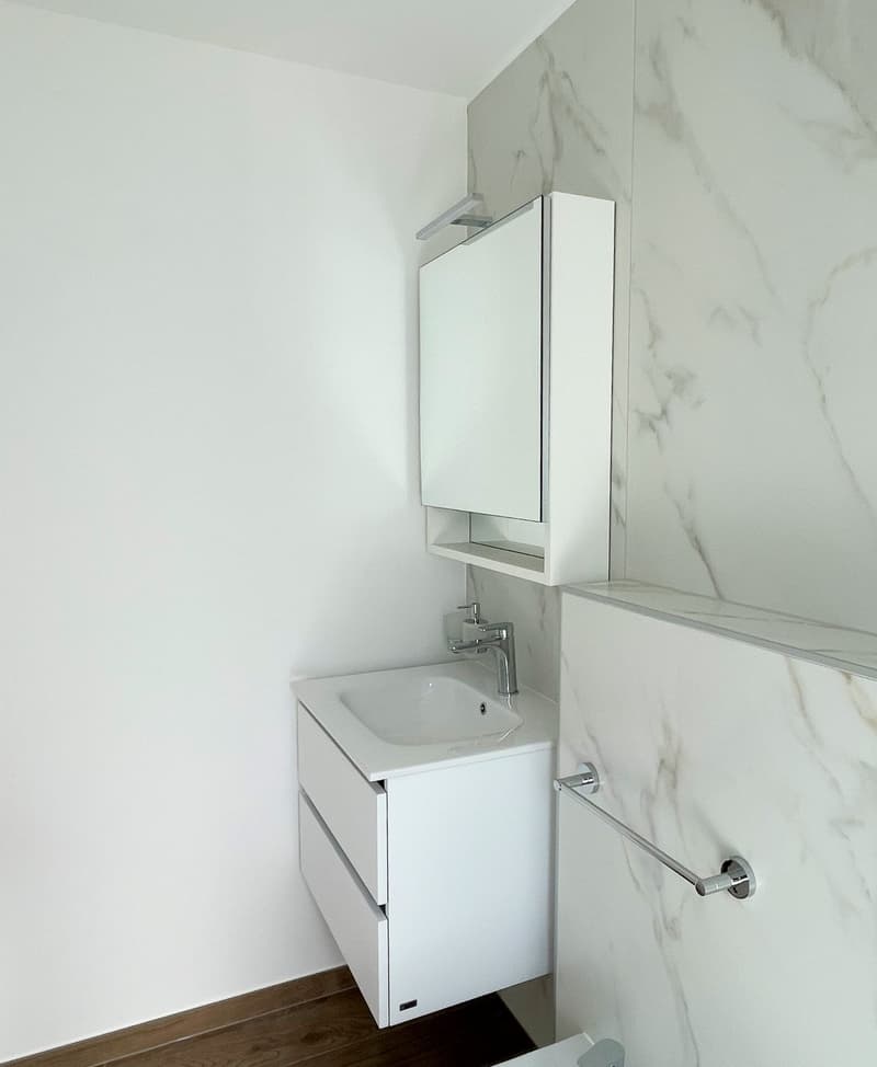 White marble walls, white countertop, sink, wall-mounted cabinet with mirror, silver faucet