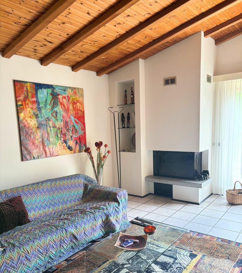 Living room with fireplace, couch, table, painting, floor, and decorative objects