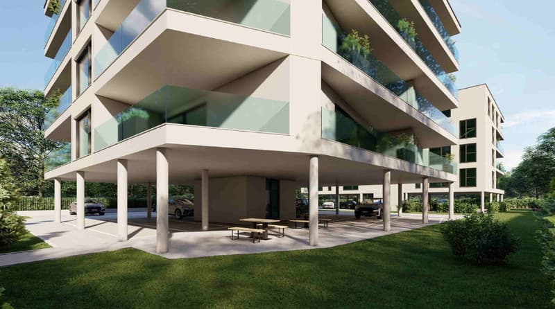 Modern apartment building with glass balconies, underground parking, and a green lawn