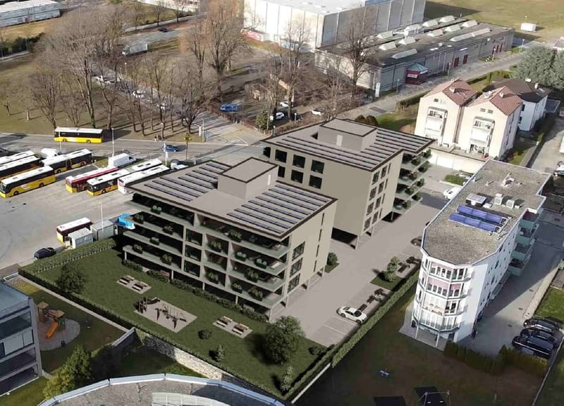 Aerial view of a multi-story building with solar panels on the roof, balconies, and a parking area.