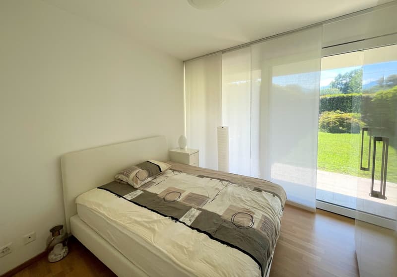 Bedroom with bed, nightstand, lamp, sliding glass door, and garden view