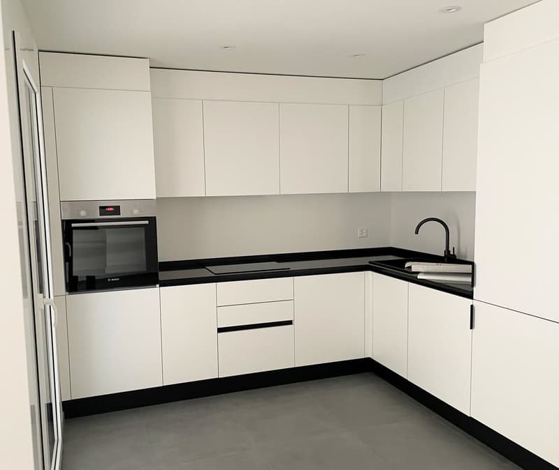 modern kitchen with white cabinets, black countertops, integrated oven, dishwasher, sink, faucet