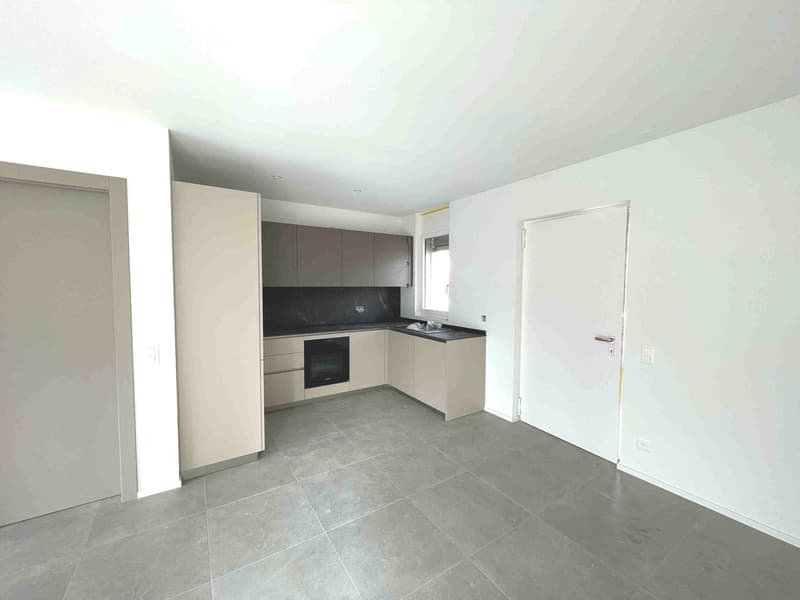 Empty kitchen with tiled floor, white walls, built-in cabinets, countertop, sink, oven, and a window.