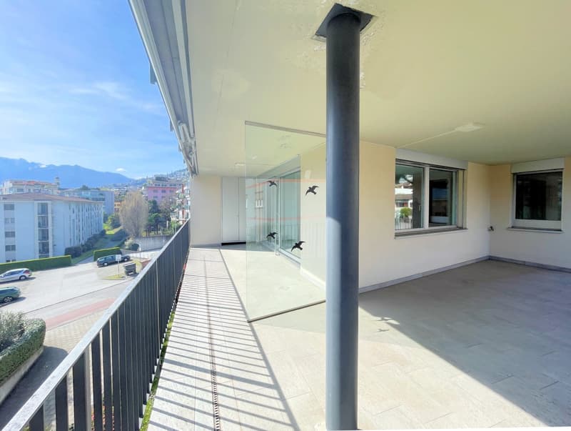 Balcony with glass railing, tiled floor, view of the mountains and buildings