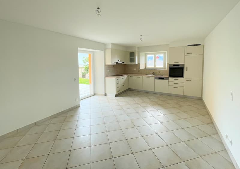 Empty kitchen with white tiles, white cabinets, and a glass door leading to a patio.