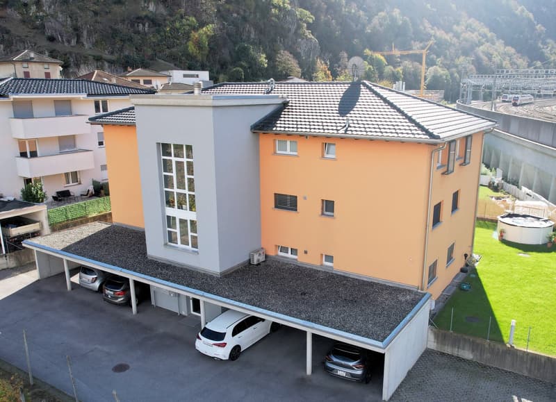 3 story house, orange and white, 3 cars in garage, green lawn, mountain in background