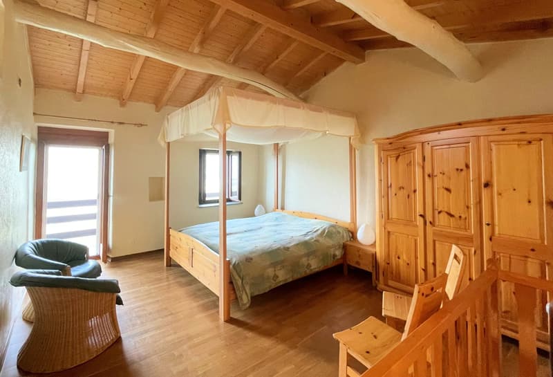 bedroom with wooden bed, canopy, wooden chair, wooden cabinet, wooden floor, window
