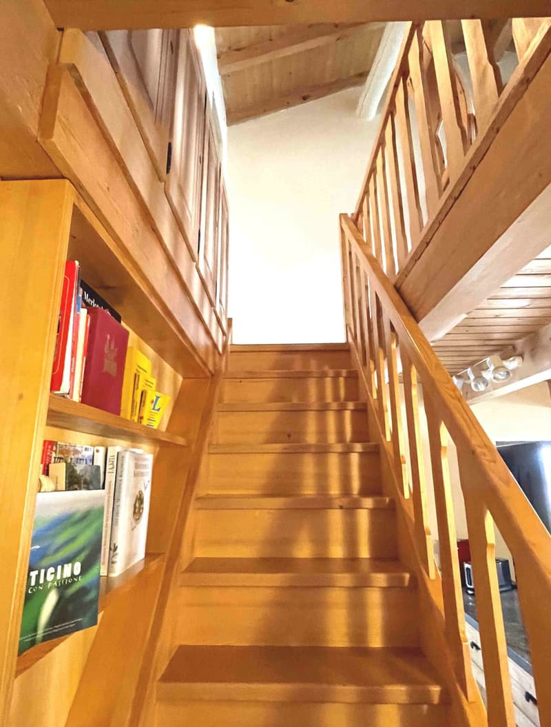 wooden staircase with wooden handrail, wooden shelves with books