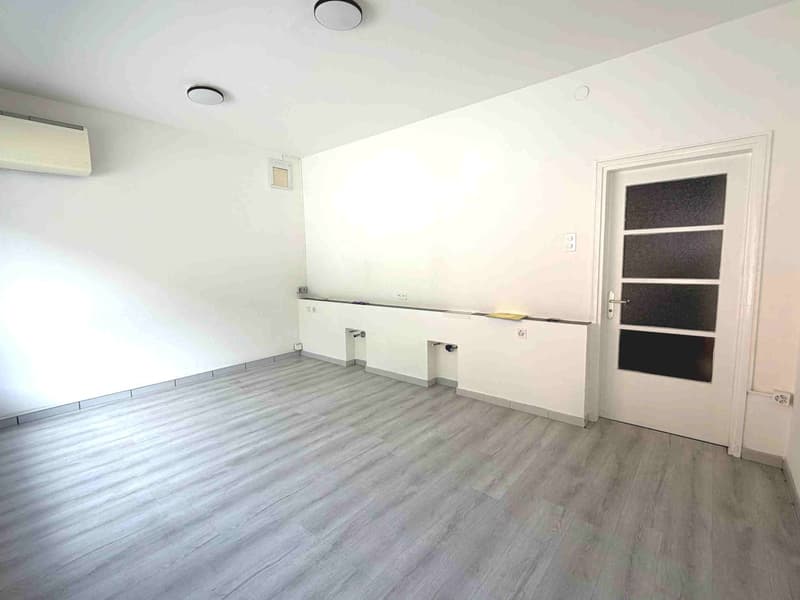empty room, white walls, gray wooden floor, white door, air conditioner, power outlets