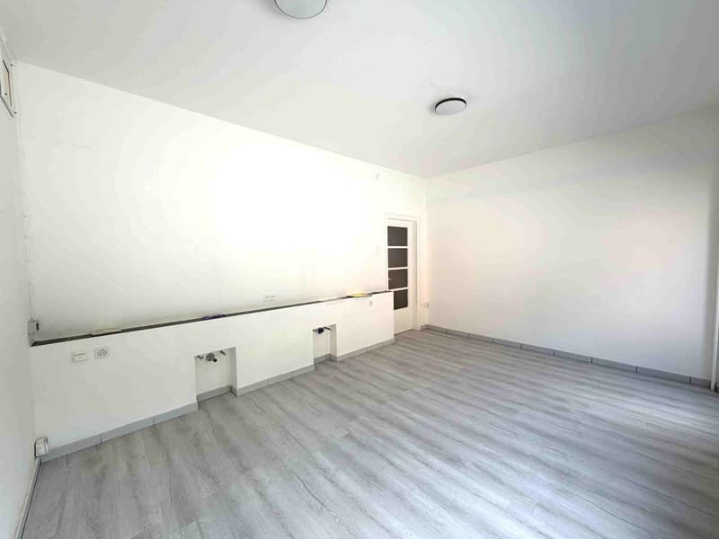 empty room, white walls, gray floor, white door, power outlets, ceiling lights