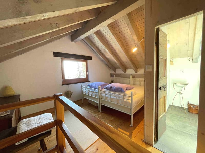 bedroom with two single beds, wooden ceiling, wooden floor, window, wooden railing, lamp