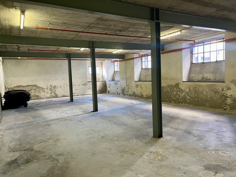 empty building space, concrete floor, support columns, exposed pipes and wires, 4 windows