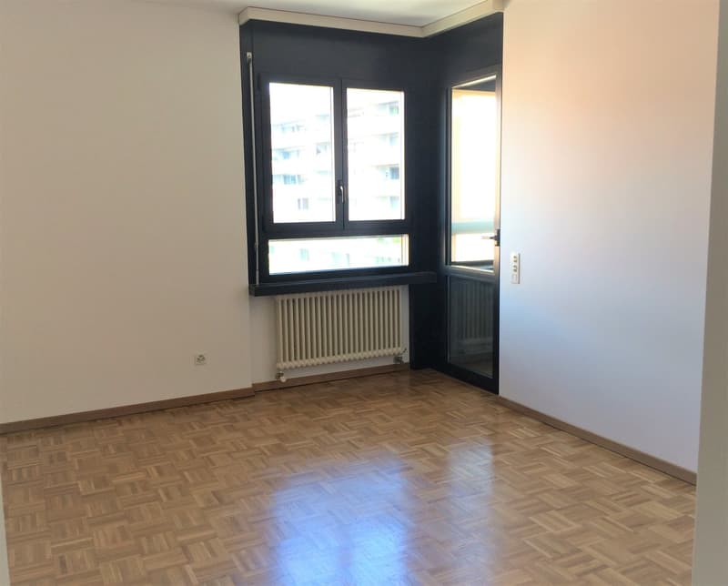 Empty room with hardwood flooring, white walls, and a large window. The room appears to be a living room or bedroom.