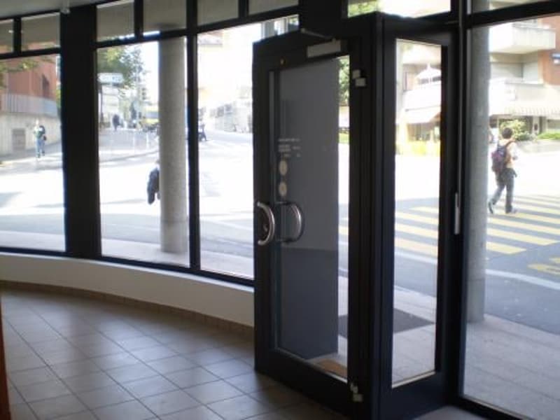 Entrance to a building with large glass windows, tile floor, and a view of the street
