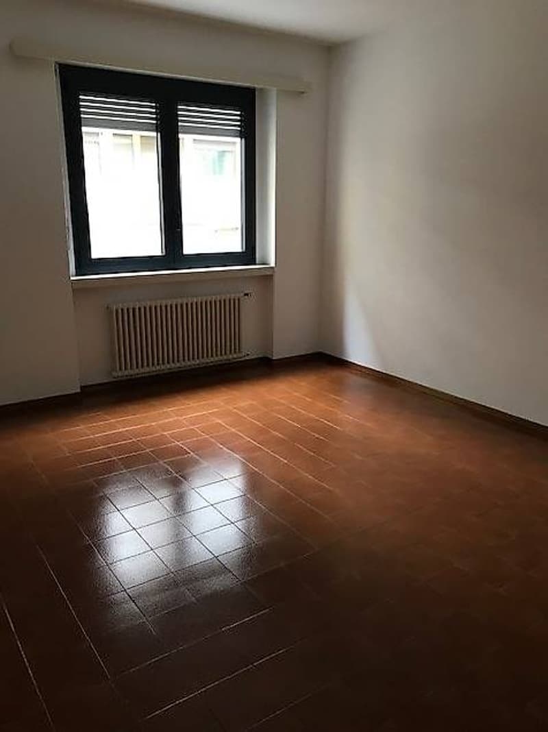 room with window, radiator, and brown tiled floor