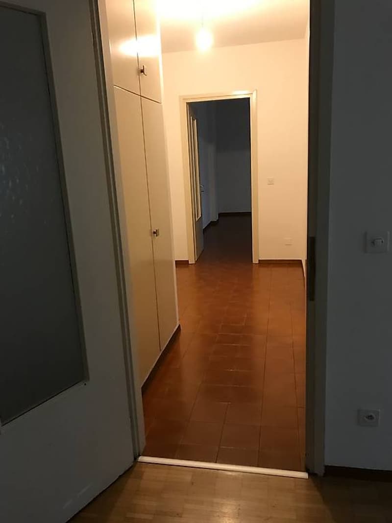 Empty hallway, tiled floor, white walls, two doors