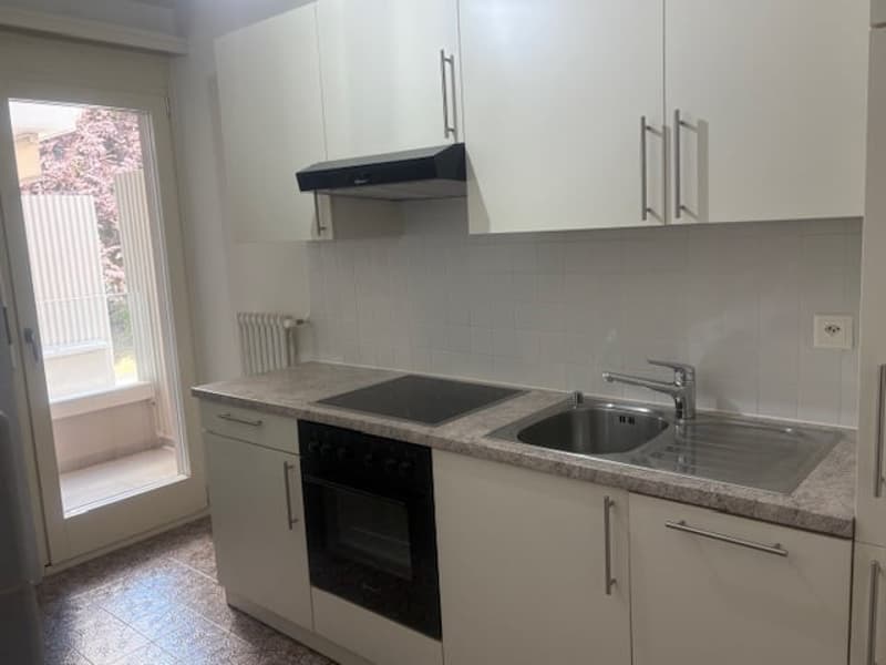 modern kitchen with white cabinets, granite countertop, black stove, oven, stainless steel sink, faucet, and a window with a view