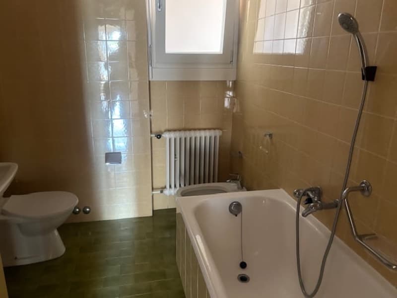 Bathroom with bathtub, toilet, bidet, radiator, tiled walls and floor