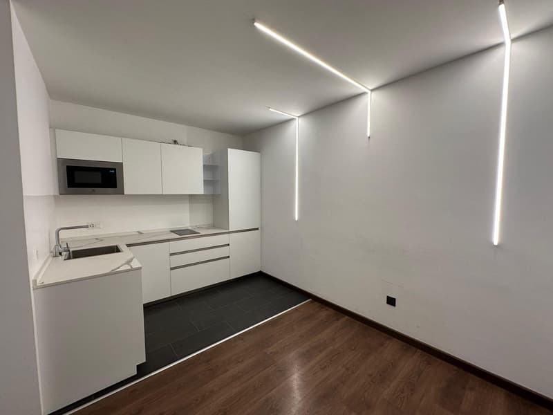 modern kitchen with white cabinets, black tiled floor, stainless steel sink, microwave, wooden floor