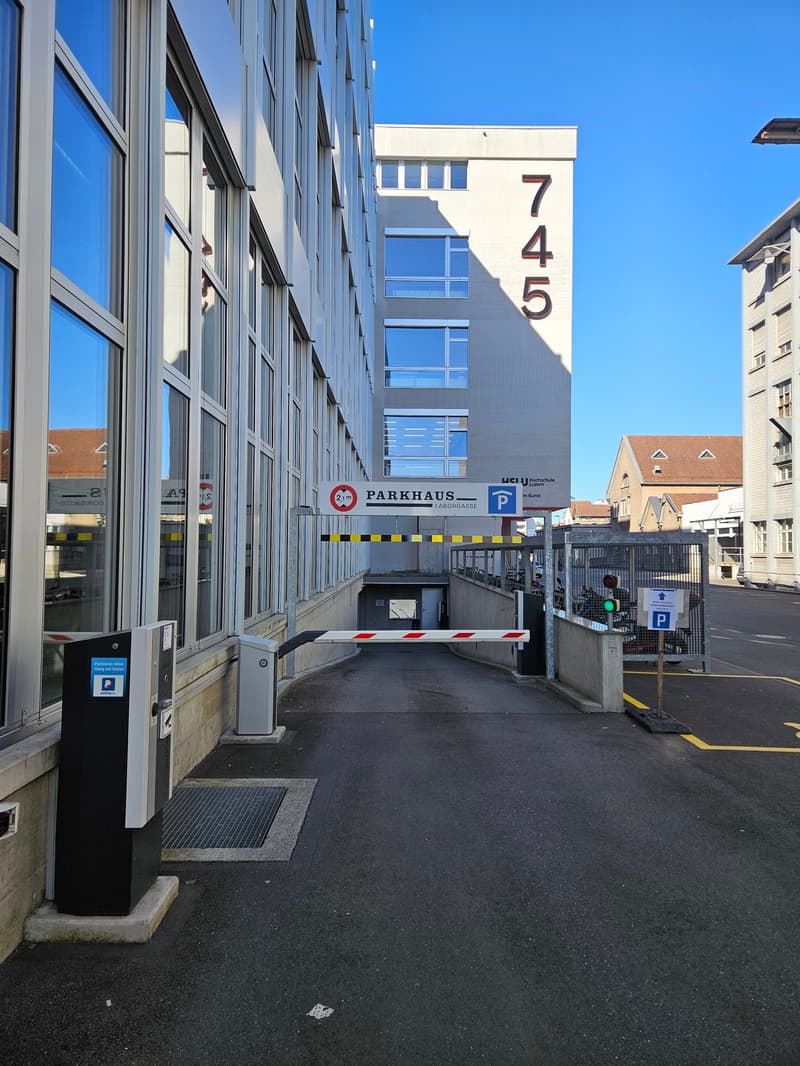 Parking facility with an entrance, an underground parking area, parking sign, a payment machine, and a parking gate.