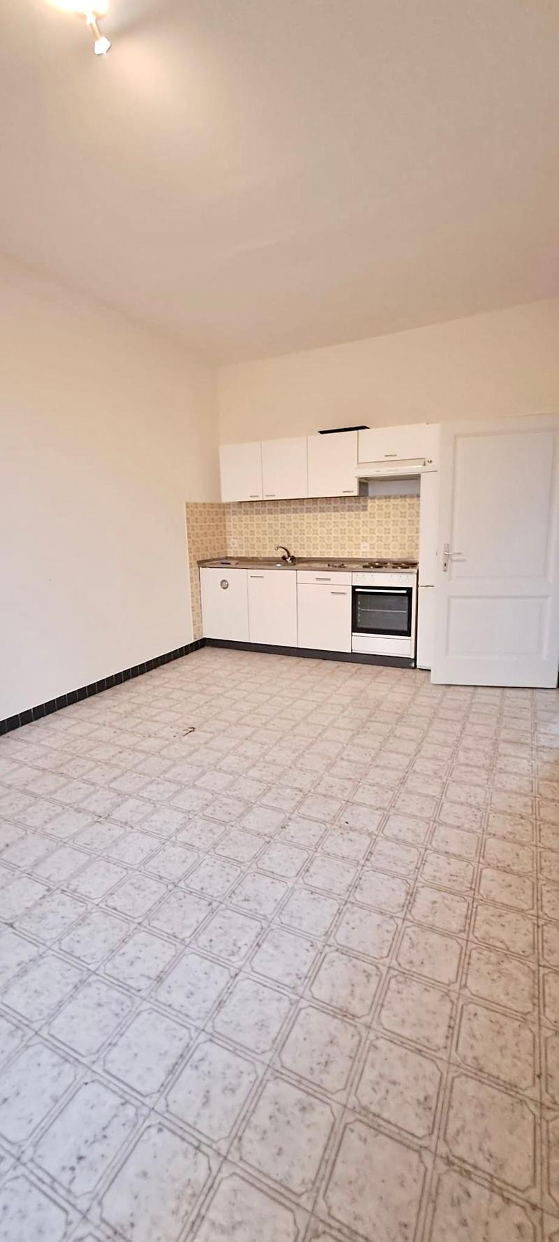 An empty kitchen, tile floor, countertop, sink, stove, white cabinets, an open door