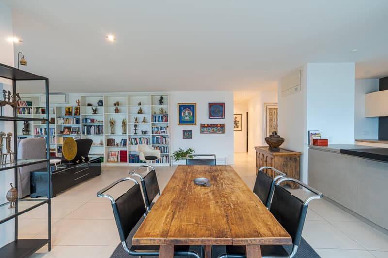 open dining area, wooden dining table, chairs, bookshelves, grey sofa, coffee table