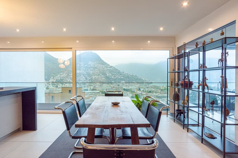 dining room with a wooden table, modern black chairs, carpet, shelf, and large windows with balcony