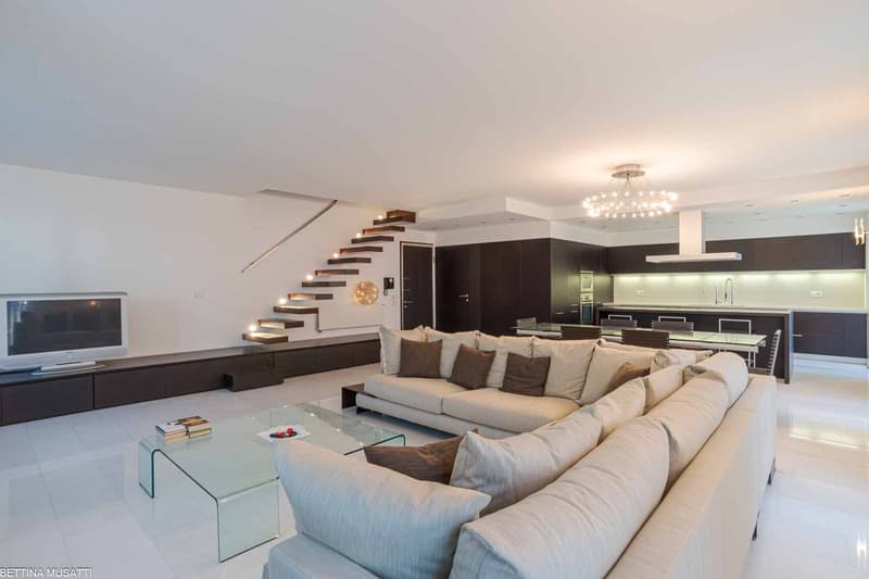 white walls, white floor, large sofa, dining table, television, cabinet with television