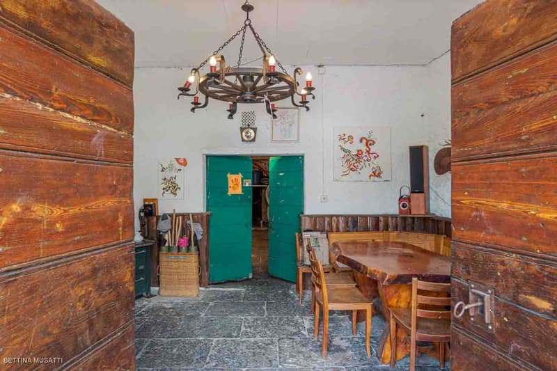 wooden paneling, chandelier, wooden table and chairs, open doors, storage box, paintings on wall