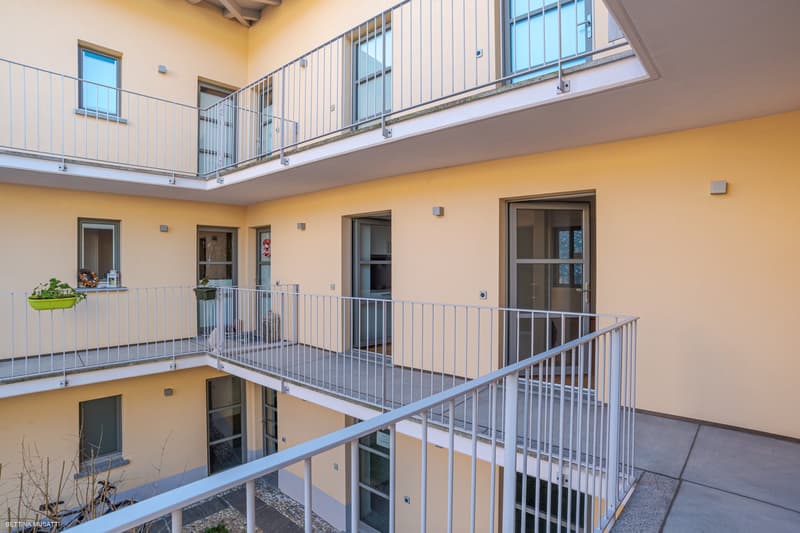 two balconies, multiple windows, beige painted wall, raised ground floor