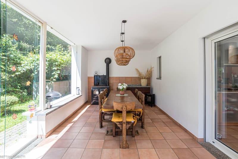 dining room with large windows, wooden table, chairs, fireplace, tiled floor, pendant lights