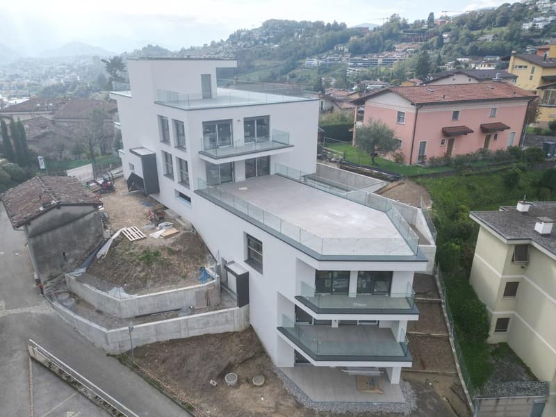White modern building with a raised ground floor, terraces, and a swimming pool