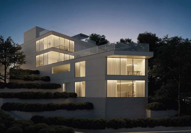 Modern multi-story house with large windows, balconies, and a landscaped garden area in front.