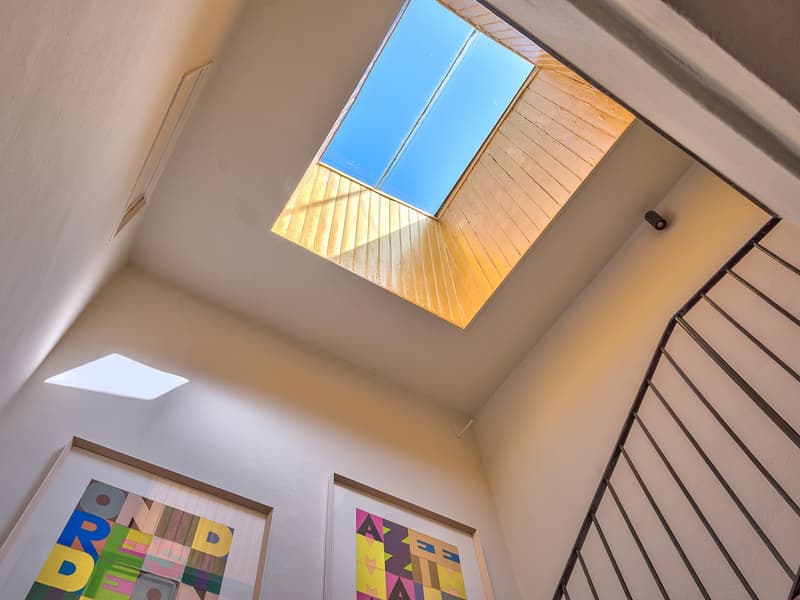 Skylight with wooden lining, metal railing, two paintings, ceiling lights