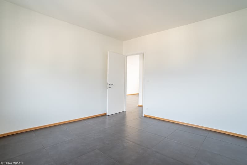 empty room, white walls, gray tiles, open door, doorway to another room