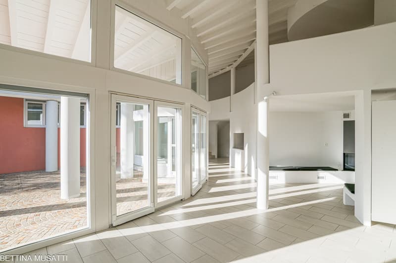 Wide hallway, big windows, sliding doors, white walls and ceiling, light wooden flooring