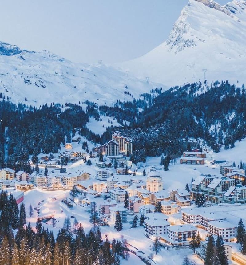 Snowy mountainous landscape with a village, numerous buildings and a mountain in the background