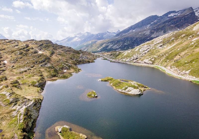 A lake surrounded by mountains, with rocks and small islands in the water.