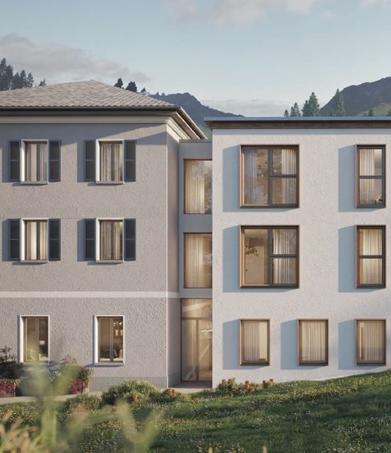 Modern white apartment building with windows, front garden with flowers, hilly mountain landscape in the background