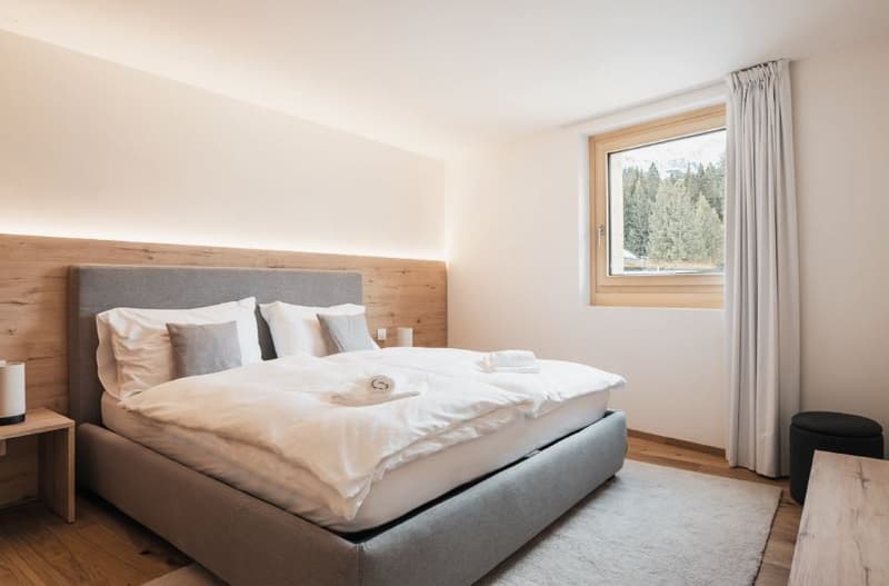 modern bedroom, double bed, white linens, wooden headboard, carpet, large window, mountain view