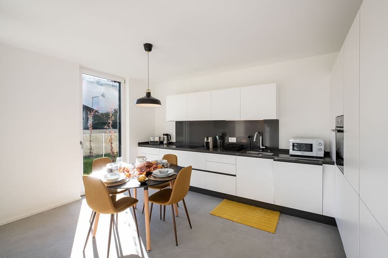 modern kitchen, white cabinets, black countertops, stainless steel appliances, dining table, chairs