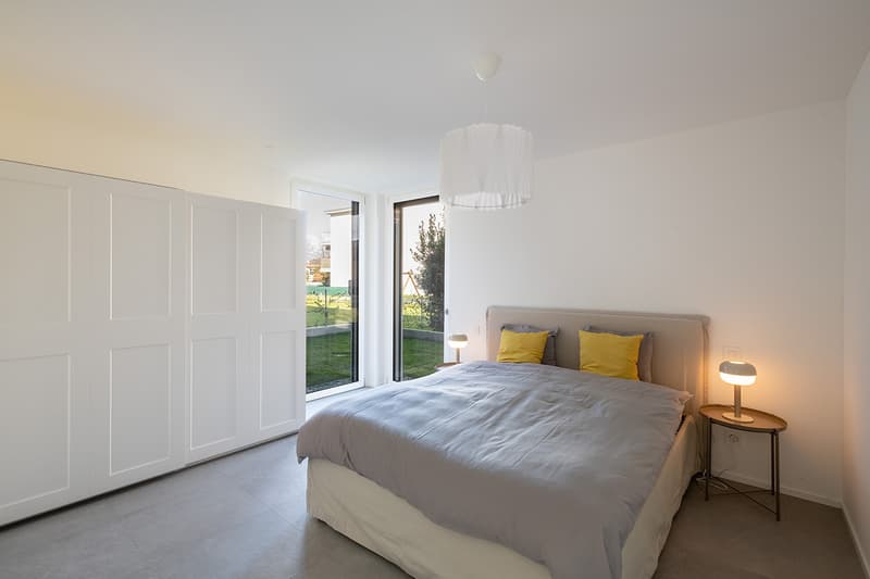 modern bedroom with white walls, gray bed, yellow pillows, white ceiling lamp, white nightstands, sliding glass doors