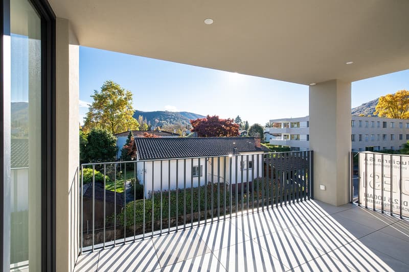 Balcony with metal railings, tiled floor, view of a house and mountains