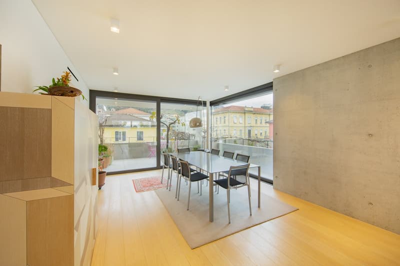 Dining room with large windows, balcony, wooden floor, table, chairs, rug, potted plants