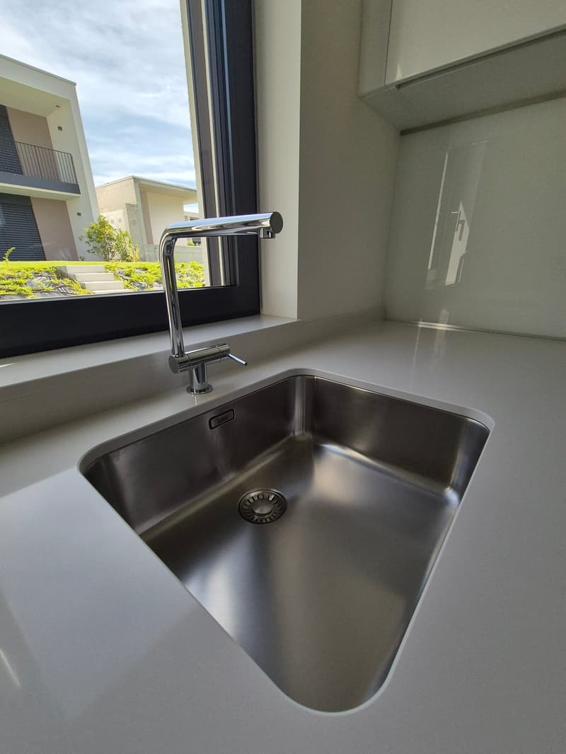Stainless steel sink with faucet, white countertop, window