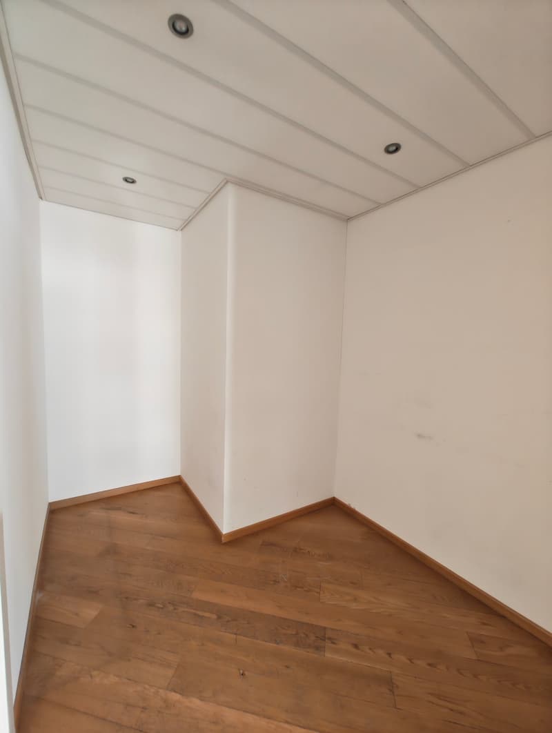 The room has a wooden floor and white walls. There are multiple lights on the ceiling, adding to the room's brightness.
