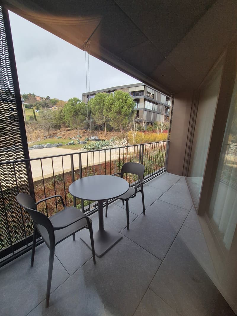 Balcony with table and chairs, black railing, city view