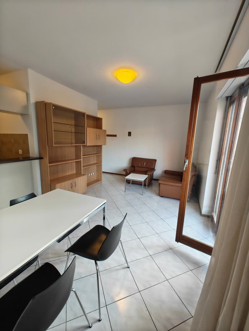 modern room with white tiles, wooden cabinet, brown leather couch, white table, black chairs