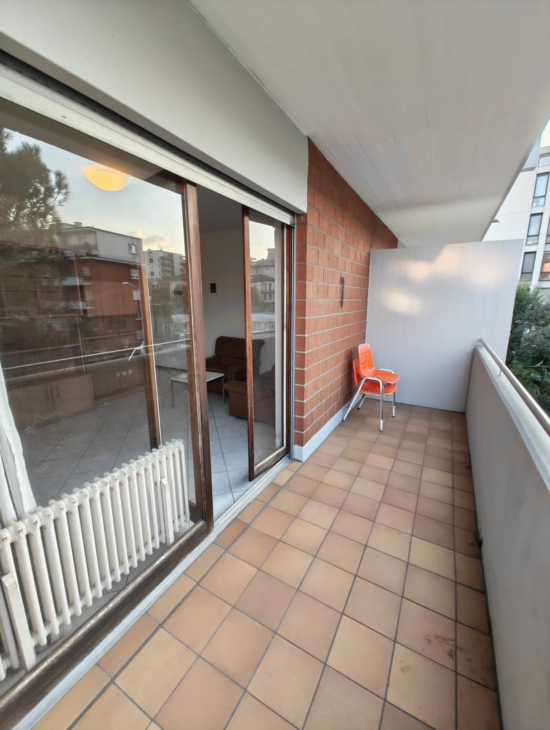 Balcony with sliding glass doors, tiled floor, white radiator, orange chairs, view of the living room